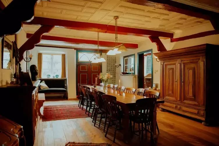 Großer Gemeinschaftsraum mit langer Tafel und Holzbalken