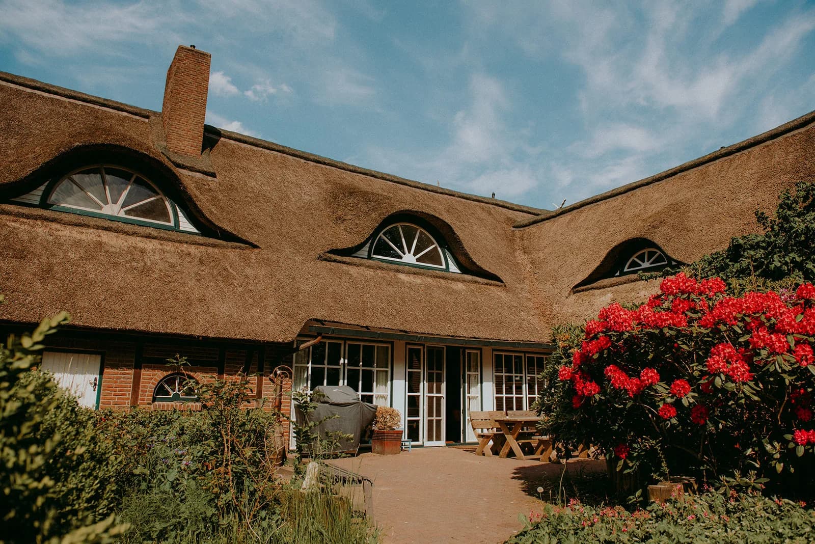 Innenhof mit Reetdach und Rhododendren